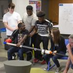 A group of students sit together testing out a mechanism 