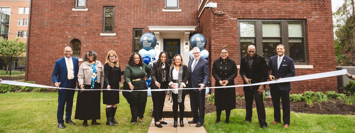 happy people lined up in front of the house about to cut a ribbon