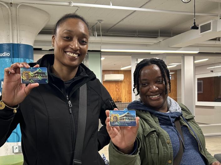 Two smiling women holding up community cards