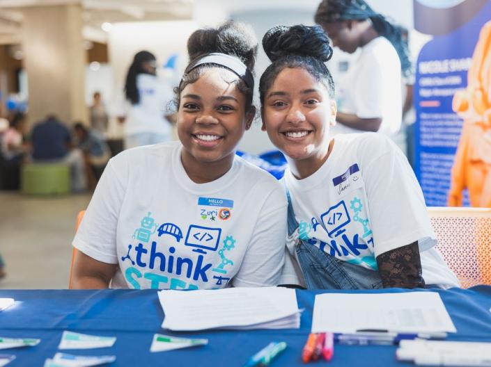 two young women sitting at a table and smiling