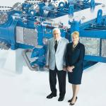 Photo of James P. Buchwald and Karen Buchwald Wright pose for a photo in front of a natural gas compressor