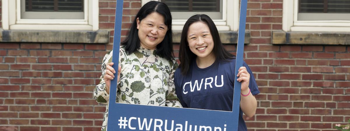 Two people posing, holding a #CWRUalumni frame