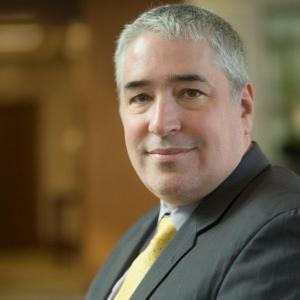 Miguel Zubizarreta headshot wearing a gray suit and gold tie