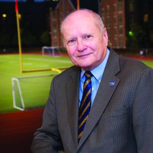 James C. Wyant smiles for camera at night wearing formal attire with a football field behind him