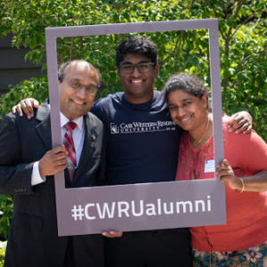Two parents and their child, who is a CWRU student, stand inside a frame that reads #CWRUalumni
