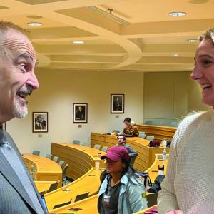 Victor Flatt and Maggie Kaniecki speak with each other in a law school lecture hall