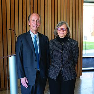 Kevin Kranzusch and Lynne Bosworth smile at camera in front of a podium in Olin Hall while wearing formal attire