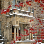 Adelbert Hall in the snow with red berries in the foreground 