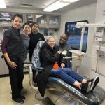Four people from CWRU School of Dental Medicine pose with a happy patient in the dentist chair