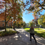 A student walks through the Mather Quad on a fall afternoon