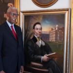 David A.G. Johnson Jr. stands beside a portrait of John Sykes Fayette while wearing formal attire