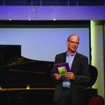 Gary Von Lehmden speaks on stage while wearing formal attire.