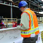 Construction worker handles beam used in the ISEB topping-out ceremony