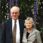 Tom and Nancy Seitz smile at camera while wearing formal attire in an outdoor setting