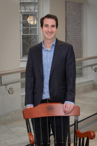 David Wald smiles at camera while standing behind a CWRU-branded chair. He is wearing formal attire.