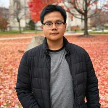 Ye Phyo stands in the Case Quad in fall, wearing a gray sweater and black jacket