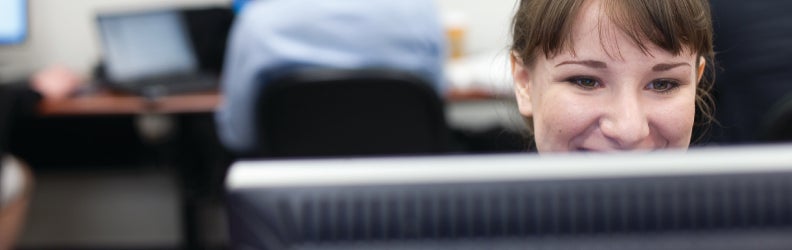 Smiling student at computer in lab