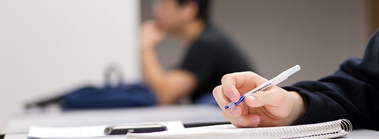 Student taking notes by hand in class