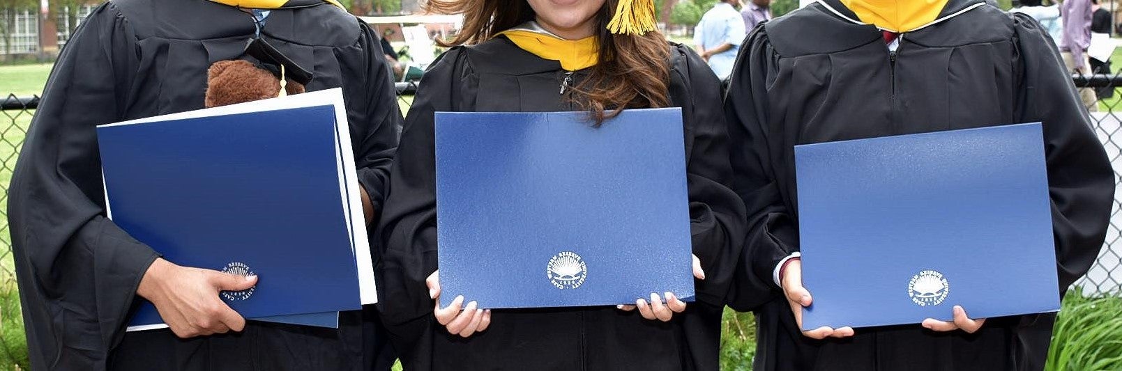 Three Masters Students Holding Diplomas at Commencement 2019