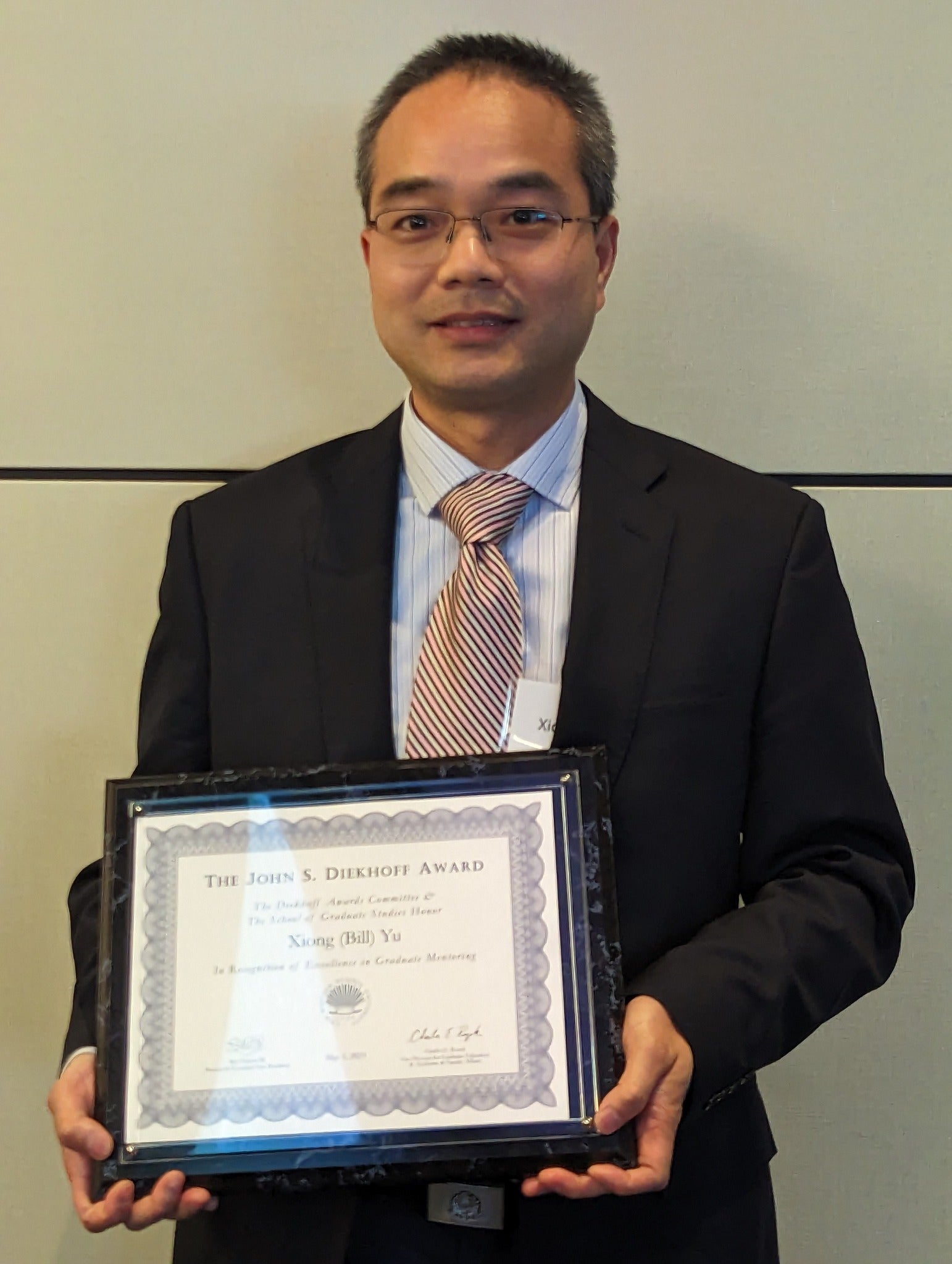 photo of professor yu holding Diekhoff certificate