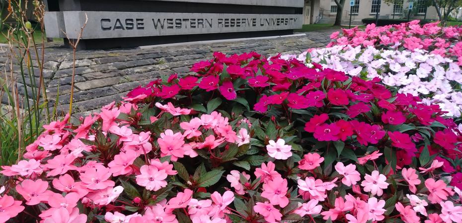 Flowers by the CWRU sign next to Crawford and Tomlinson Halls