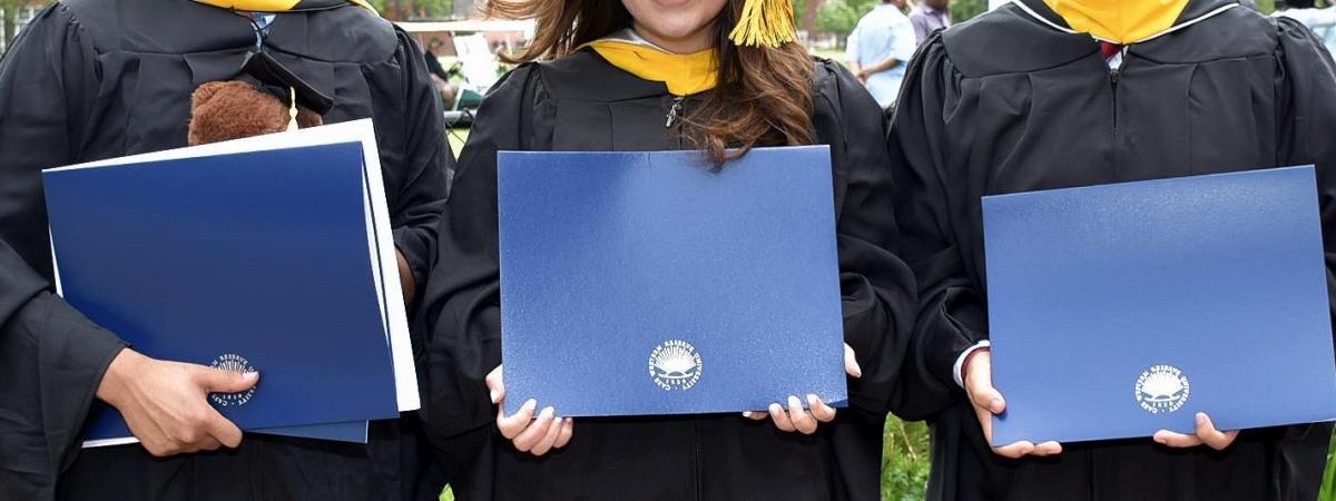 Three Masters Students Holding Diplomas at Commencement 2019
