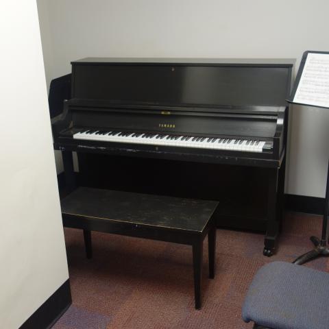 Sherman House Practice Room with common piano, music stands, and sheet music