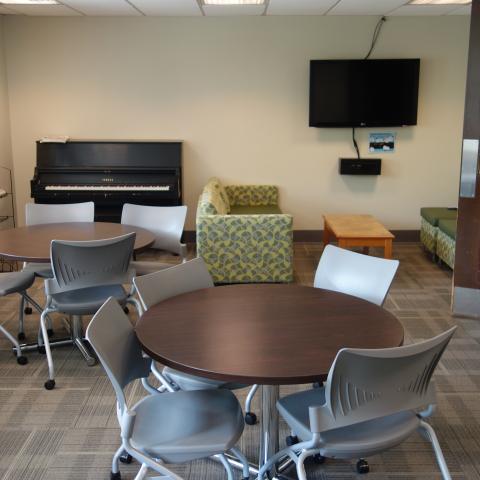 Howe House Common Room with tables, chairs, television, and common piano