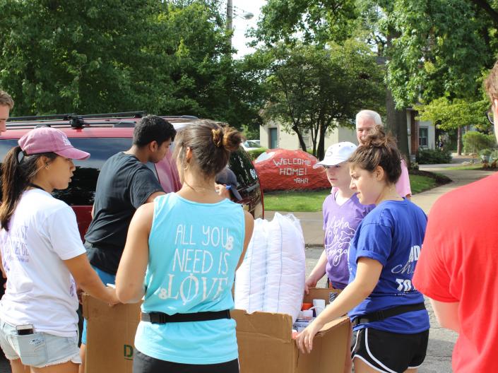 Greek Life Students assisting a freshman family move their belongings to a building