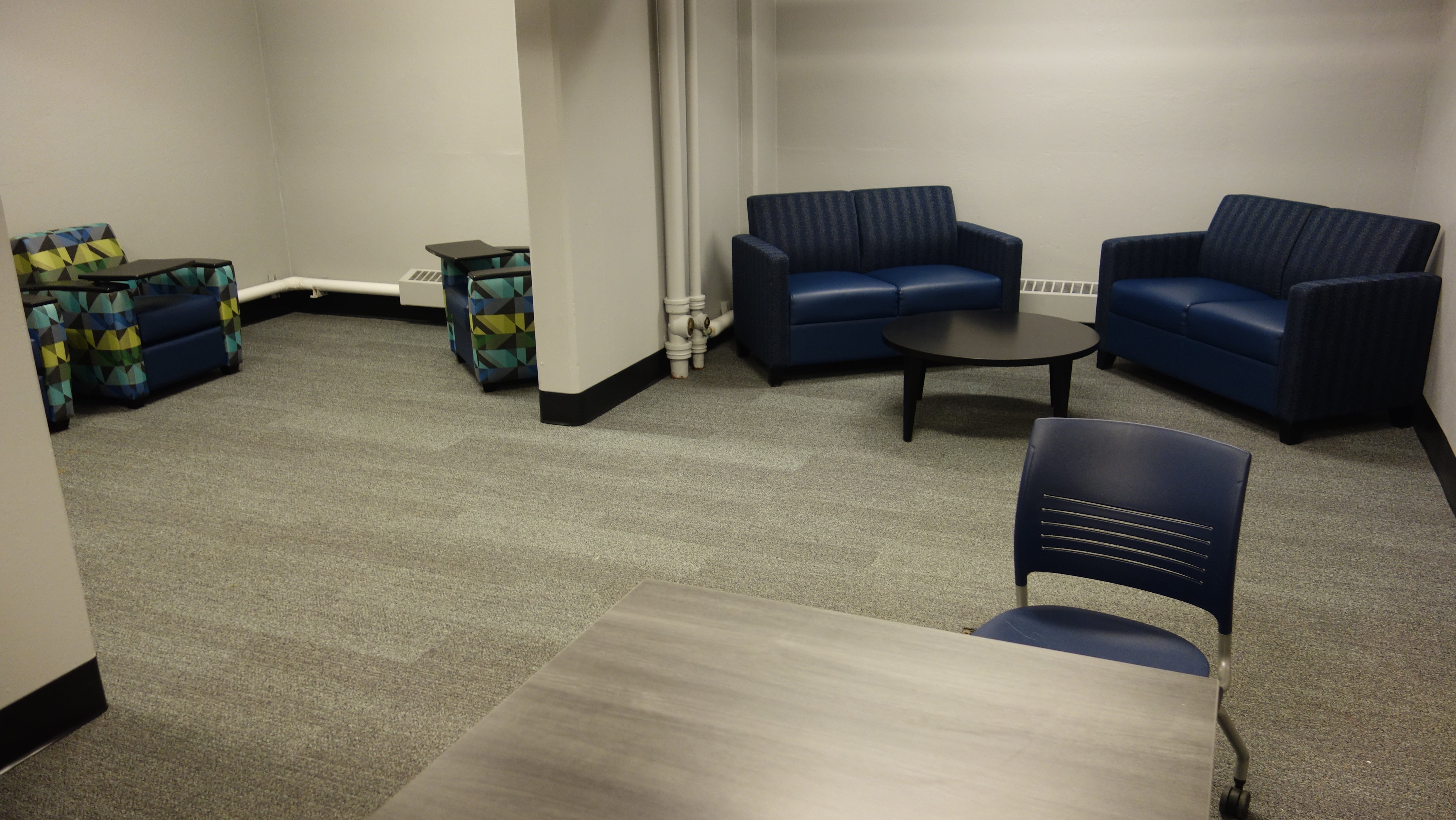 Kusch House Basement Study Lounge with table, chairs, and two-cushion couches