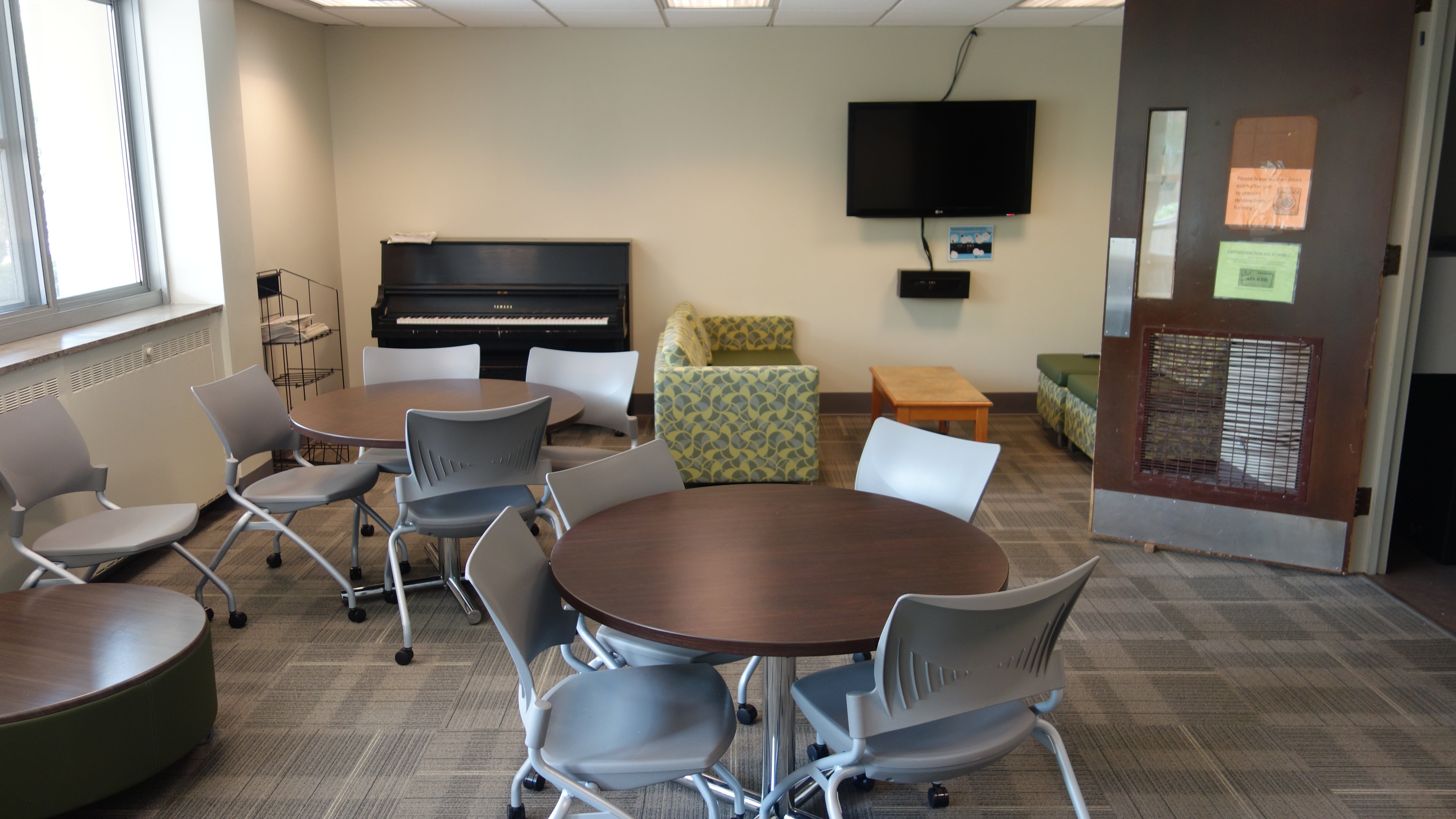 Howe House Common Room with tables, chairs, television, and common piano