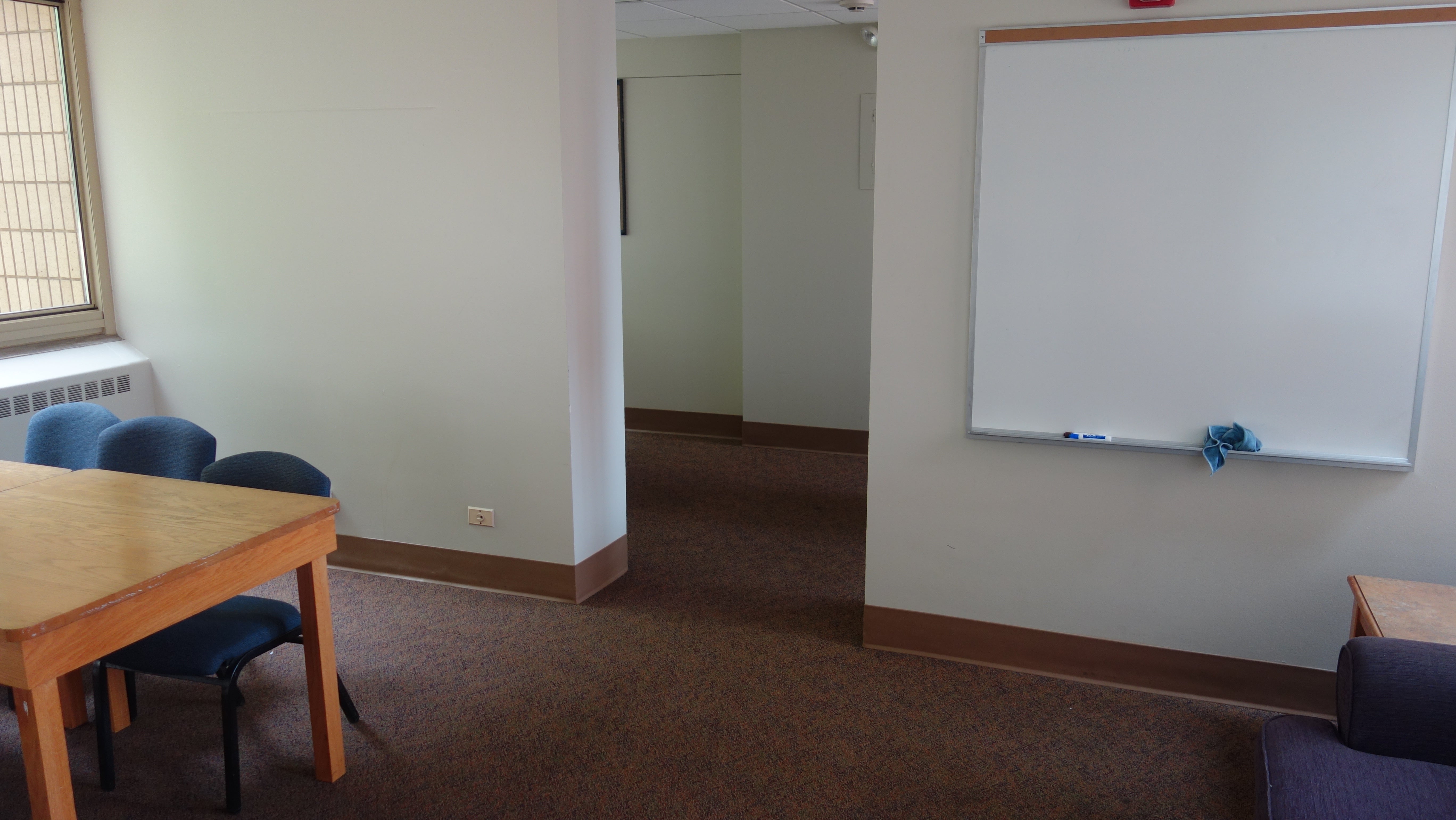 Alumni House 1st Floor Study Lounge with table, chairs, and whiteboard