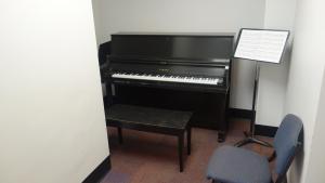 Sherman House Practice Room with common piano, music stands, and sheet music