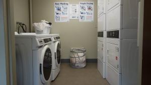 Alumni House 1st Floor Laundry Room with washers, stacked dryers, and two baskets of laundry