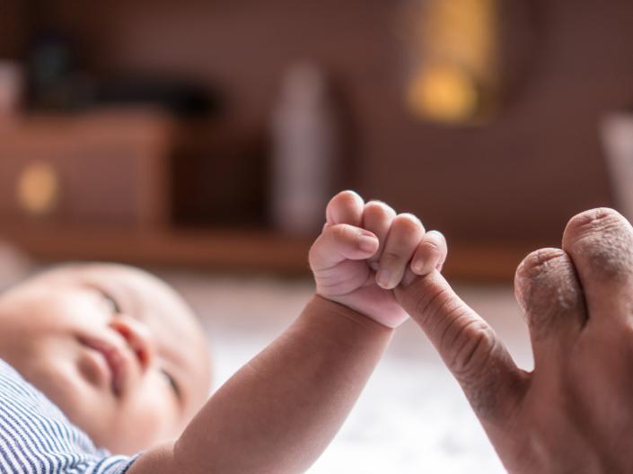 Baby holding the finger of an adult
