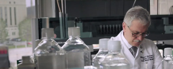 Photo of Mahmoud Ghannoum working in the lab with bottles in the foreground