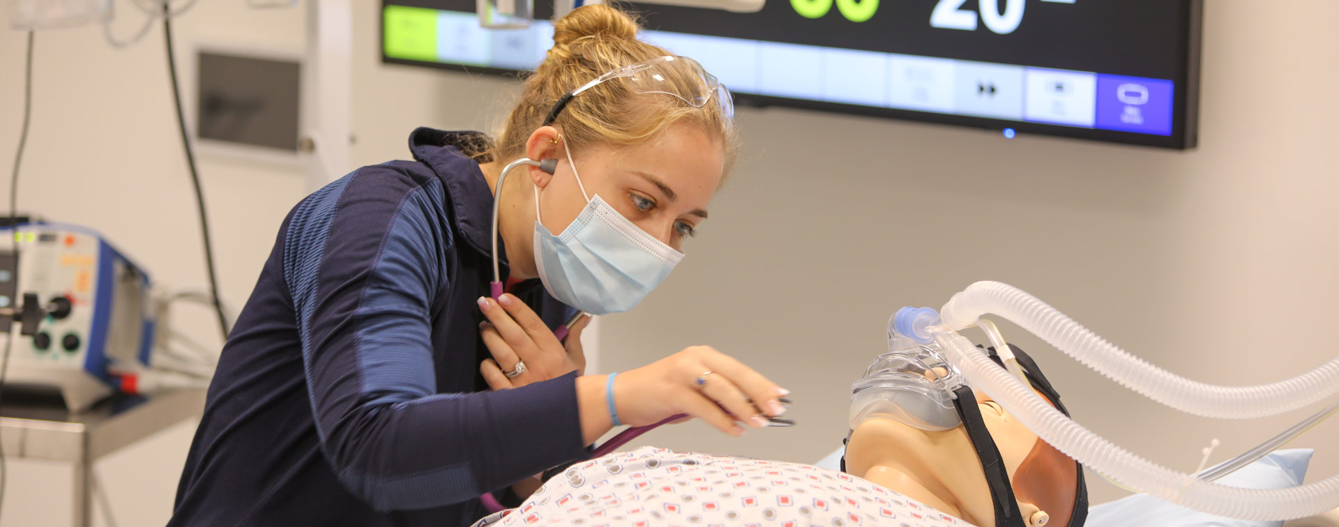 Photo of a nursing student using a stethoscope on a body mannequin