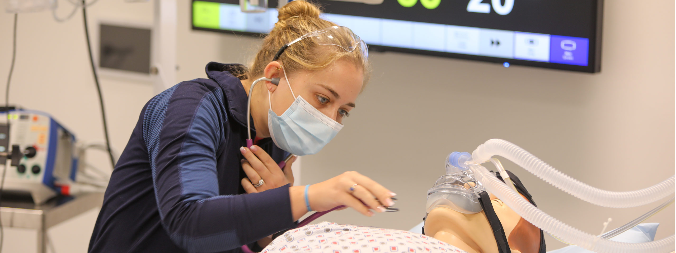 Photo of a nursing student using a stethoscope on a body mannequin