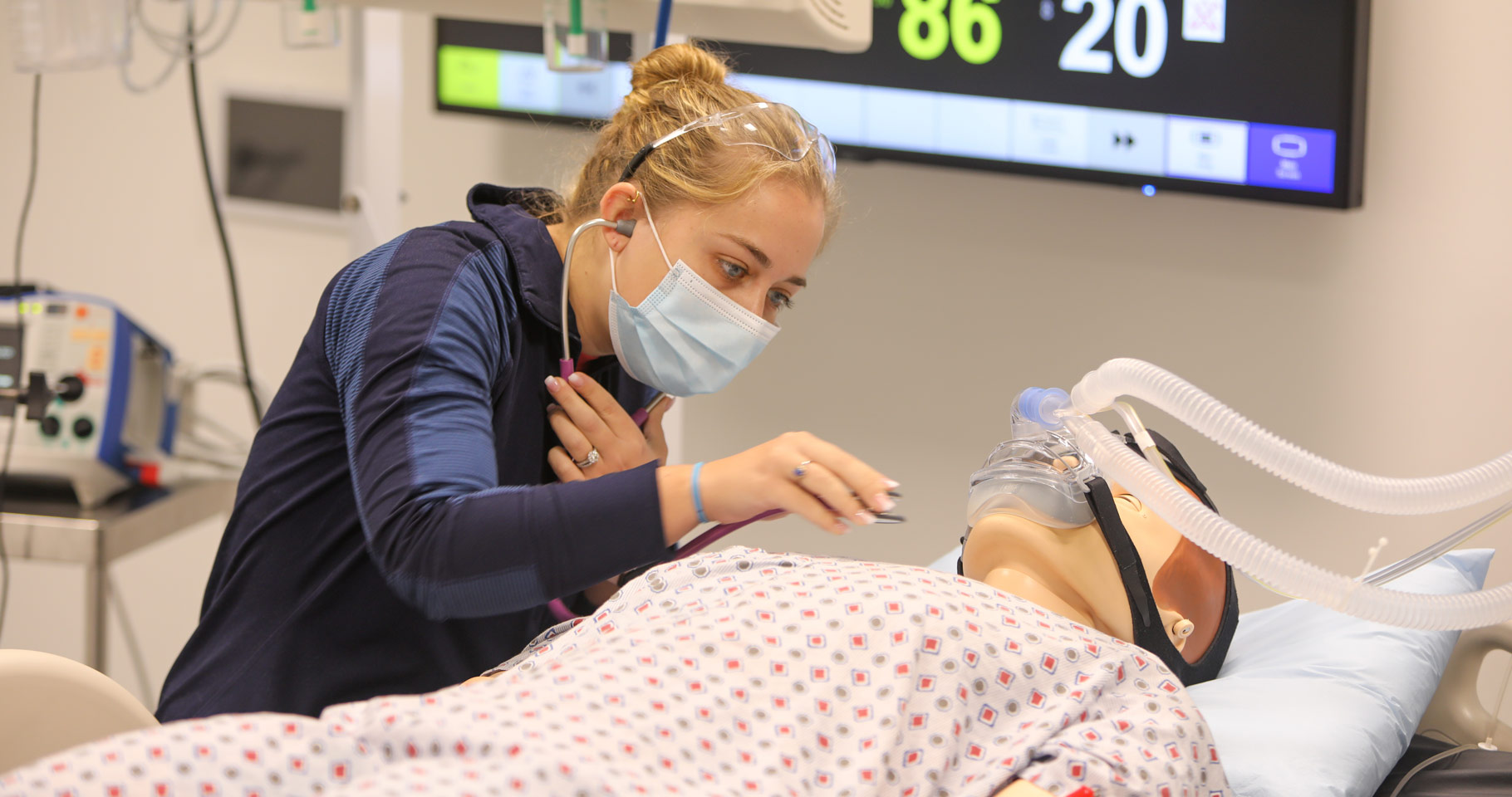 Photo of a nursing student using a stethoscope on a body mannequin