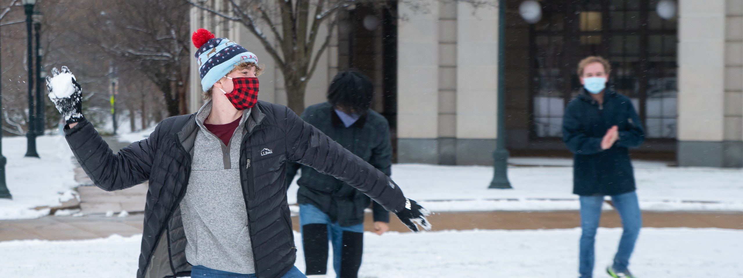 Photo of a CWRU student throwing a snowball in front of Kelvin Smith Library