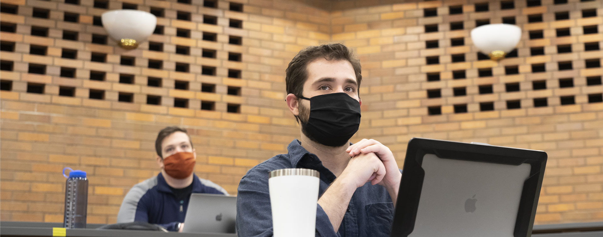 Photo of a student sitting at his laptop and looking ahead in a class at CWRU