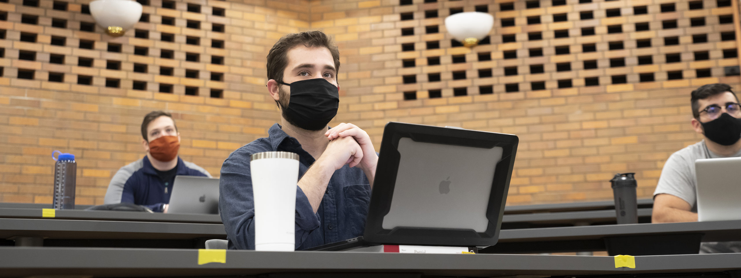 Photo of a student sitting at his laptop and looking ahead in a class at CWRU