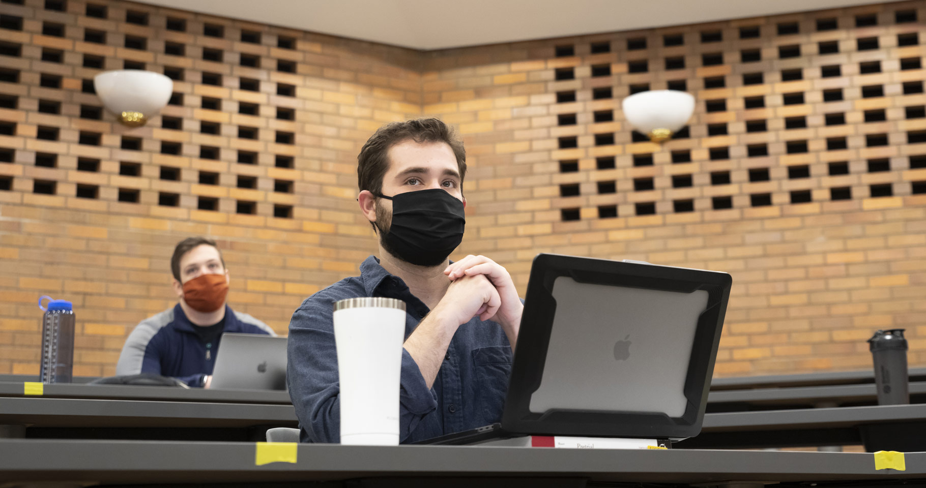 Photo of a student sitting at his laptop and looking ahead in a class at CWRU