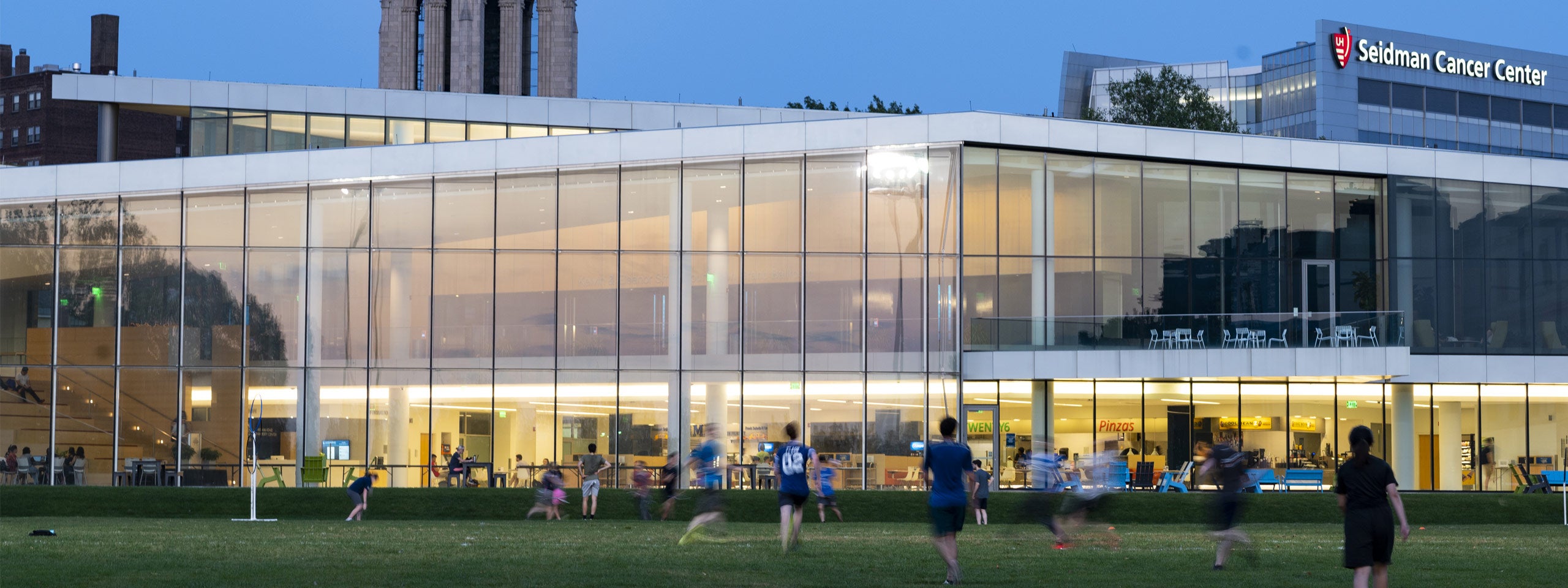 Photo of students playing a game on in the field outside Tinkham Veale University Center at dusk