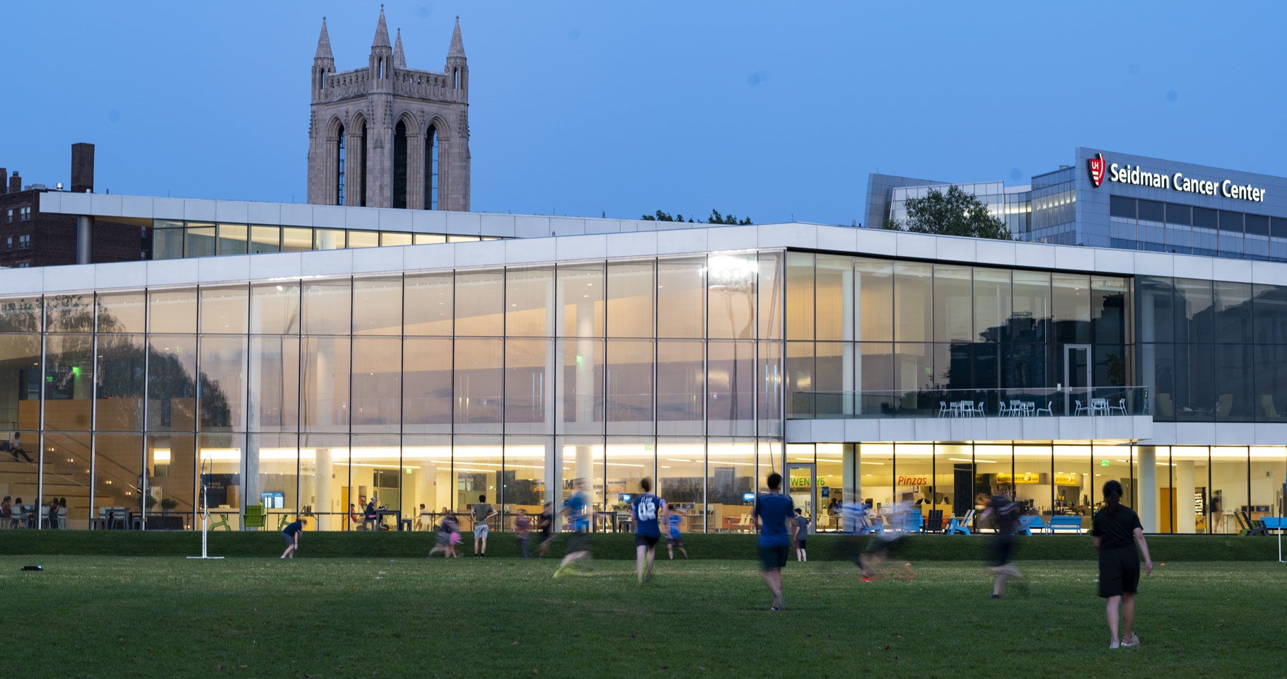 Photo of students playing a game on in the field outside Tinkham Veale University Center at dusk