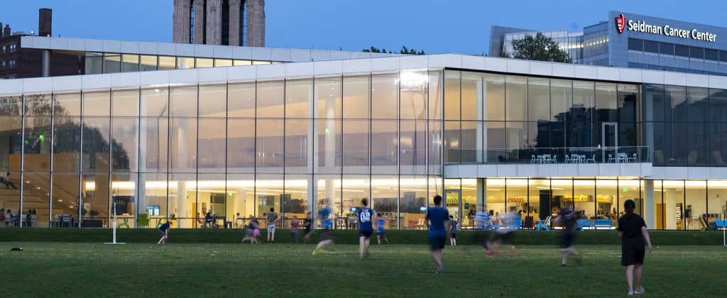 Photo of students playing a game on in the field outside Tinkham Veale University Center at dusk
