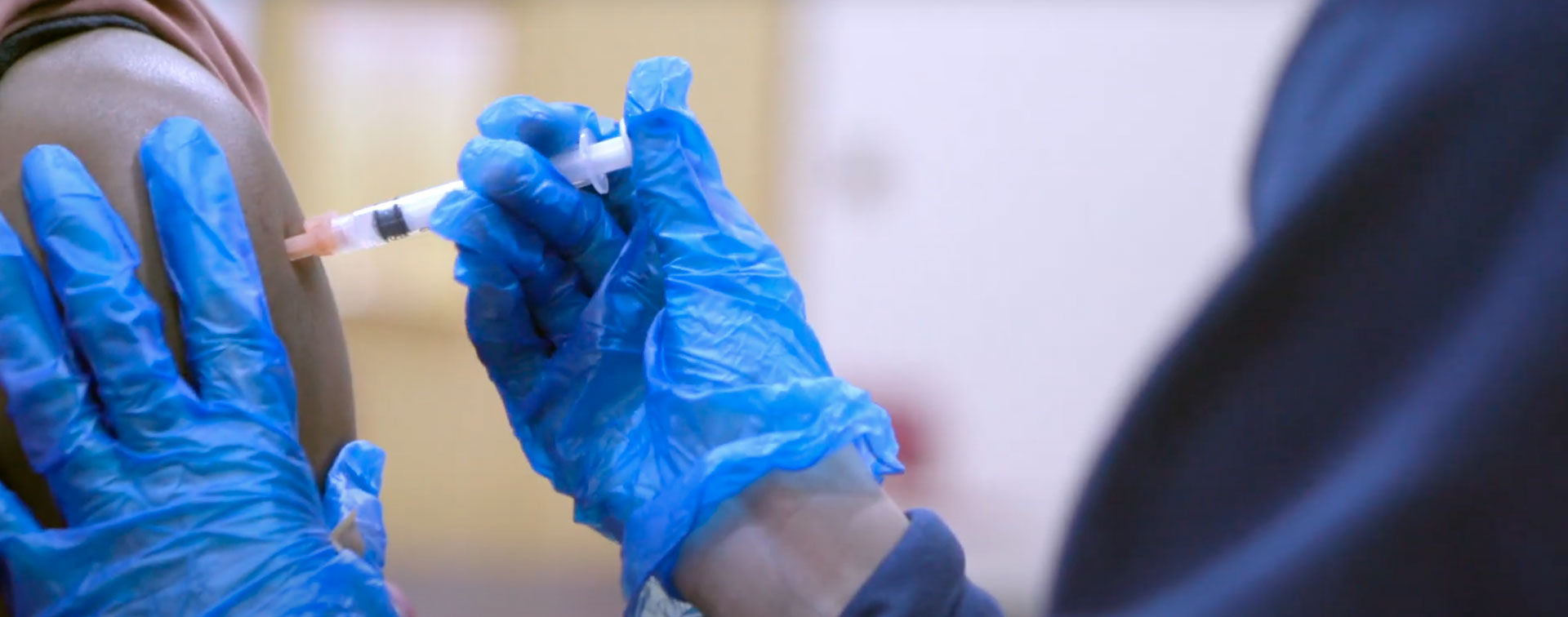 Photo of a student filling a needle from a COVID-19 vaccine vial