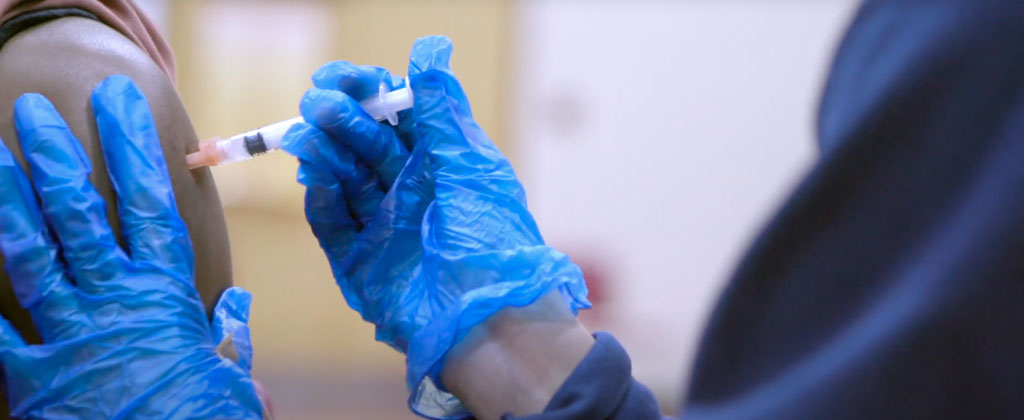 Photo of a student filling a needle from a COVID-19 vaccine vial