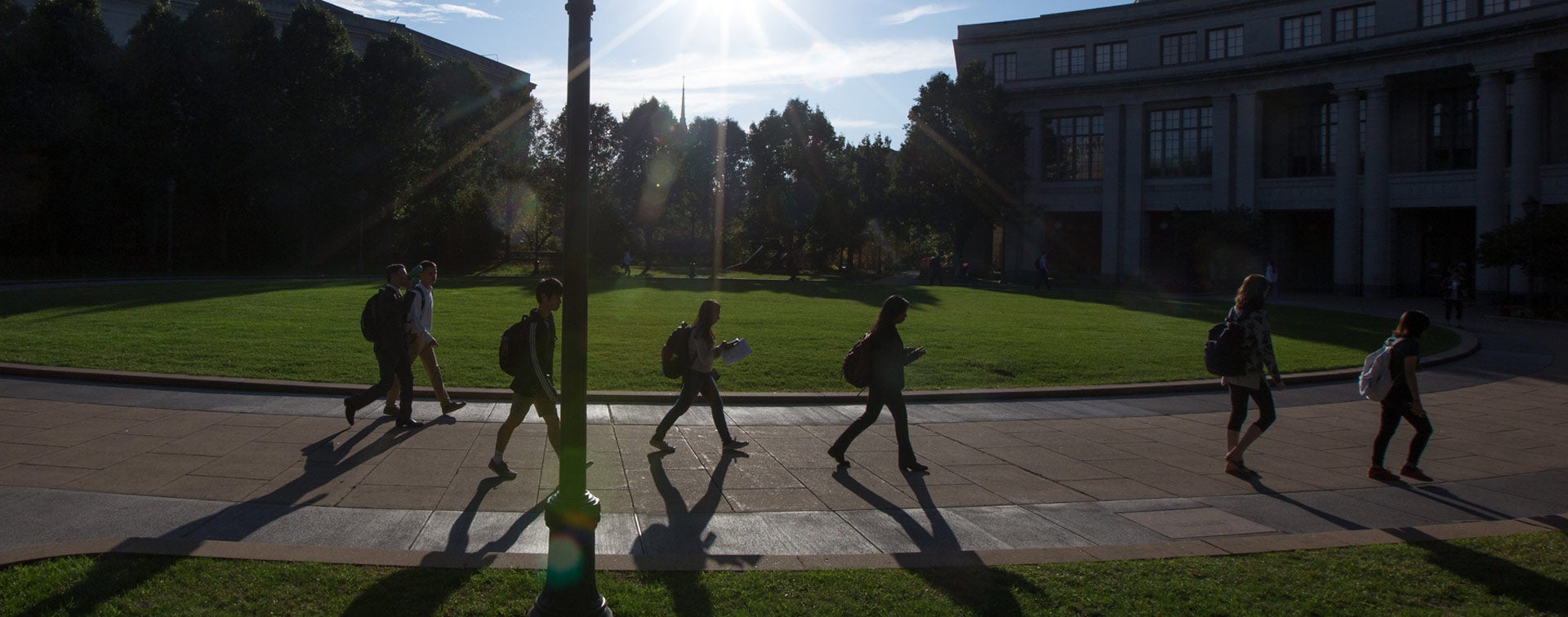 Photo of students walking at KSL Oval with the sun shining and putting a glare over the photo