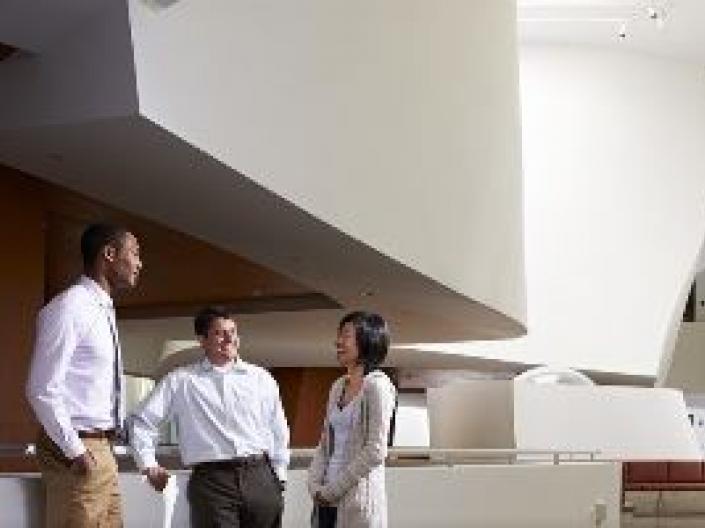 Three people standing and talking in the Peter B. Lewis Business School